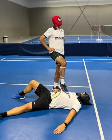 Deux membres de l’équipe Bad Hit déguisés en Spider-Man et Batman prennent la pose sur un terrain de badminton
