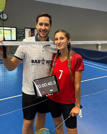 Un membre de l’équipe Bad Hit et une joueuse au filet, raquettes en main, avec la tablette qui affiche le chronomètre du record du monde&nbsp;: 20 h 00 min 40 s